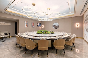 A conference room with a round table, chairs, and a chandelier.