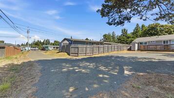 A row of wooden cabins with a gravel driveway and a clear sky.