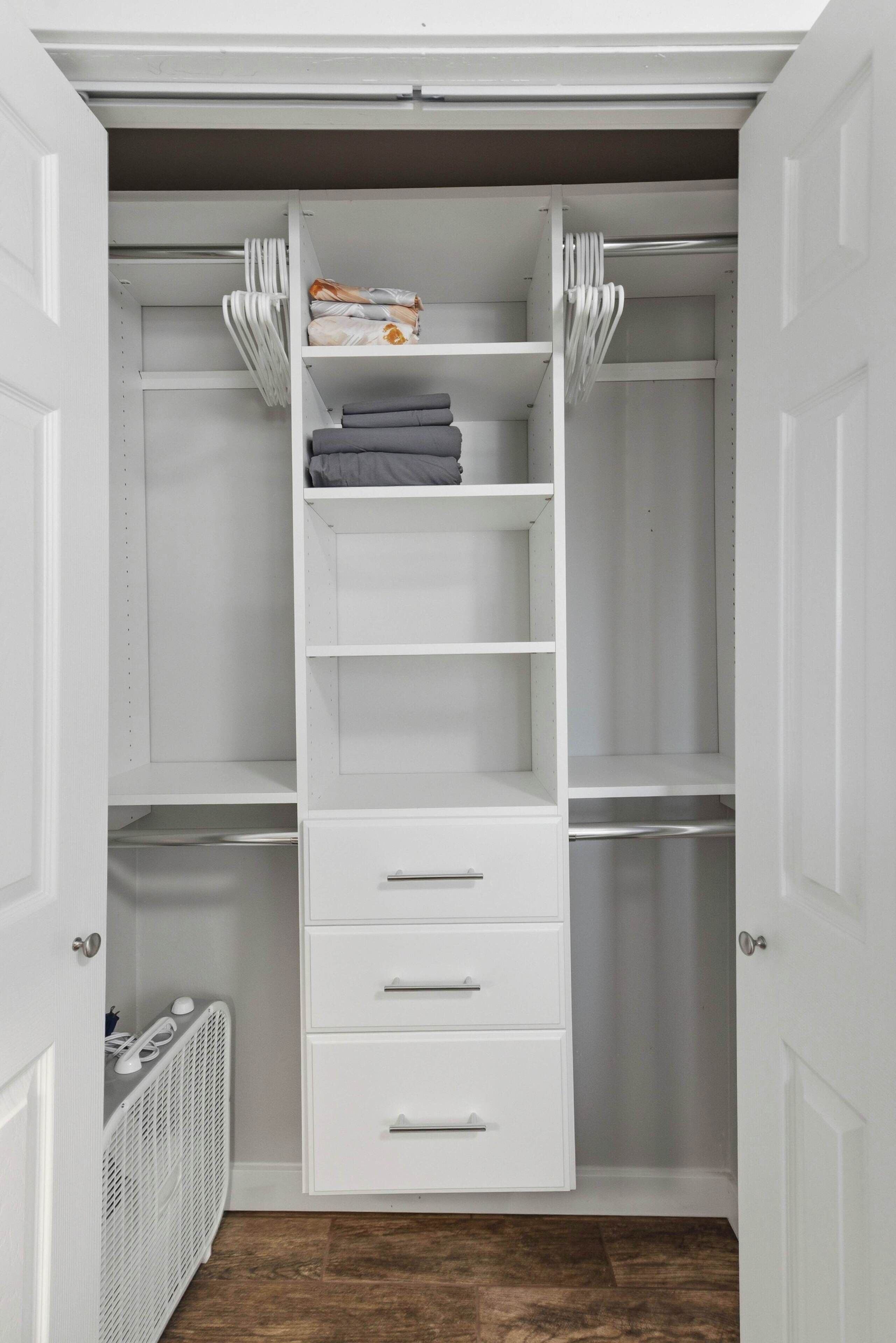 A walk-in closet with white shelving, a radiator, and a white door.