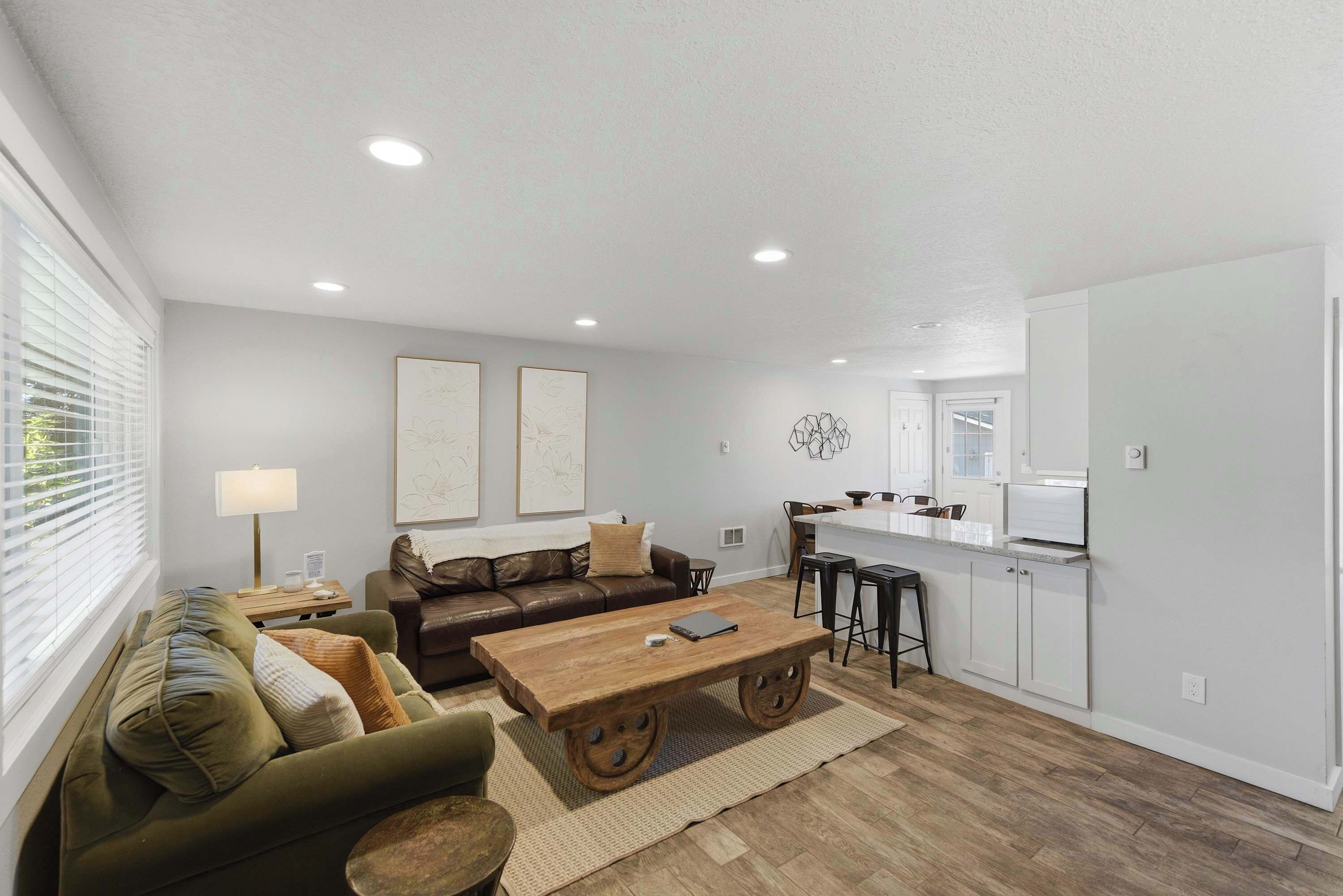 A modern living room with a sofa, coffee table, and a kitchen area with a countertop and stools.