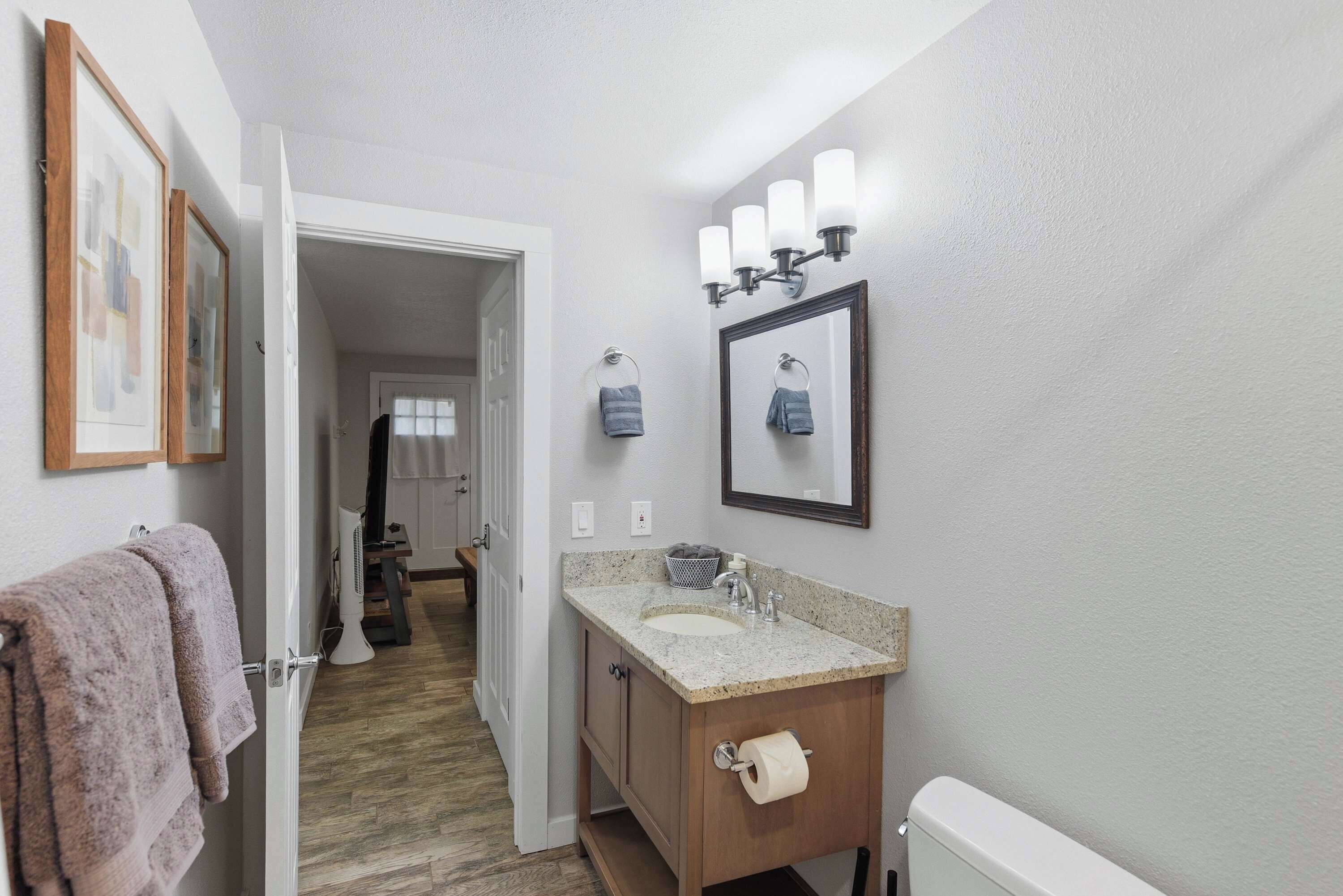 A bathroom with a sink, mirror, towel rack, and a door leading to another room.