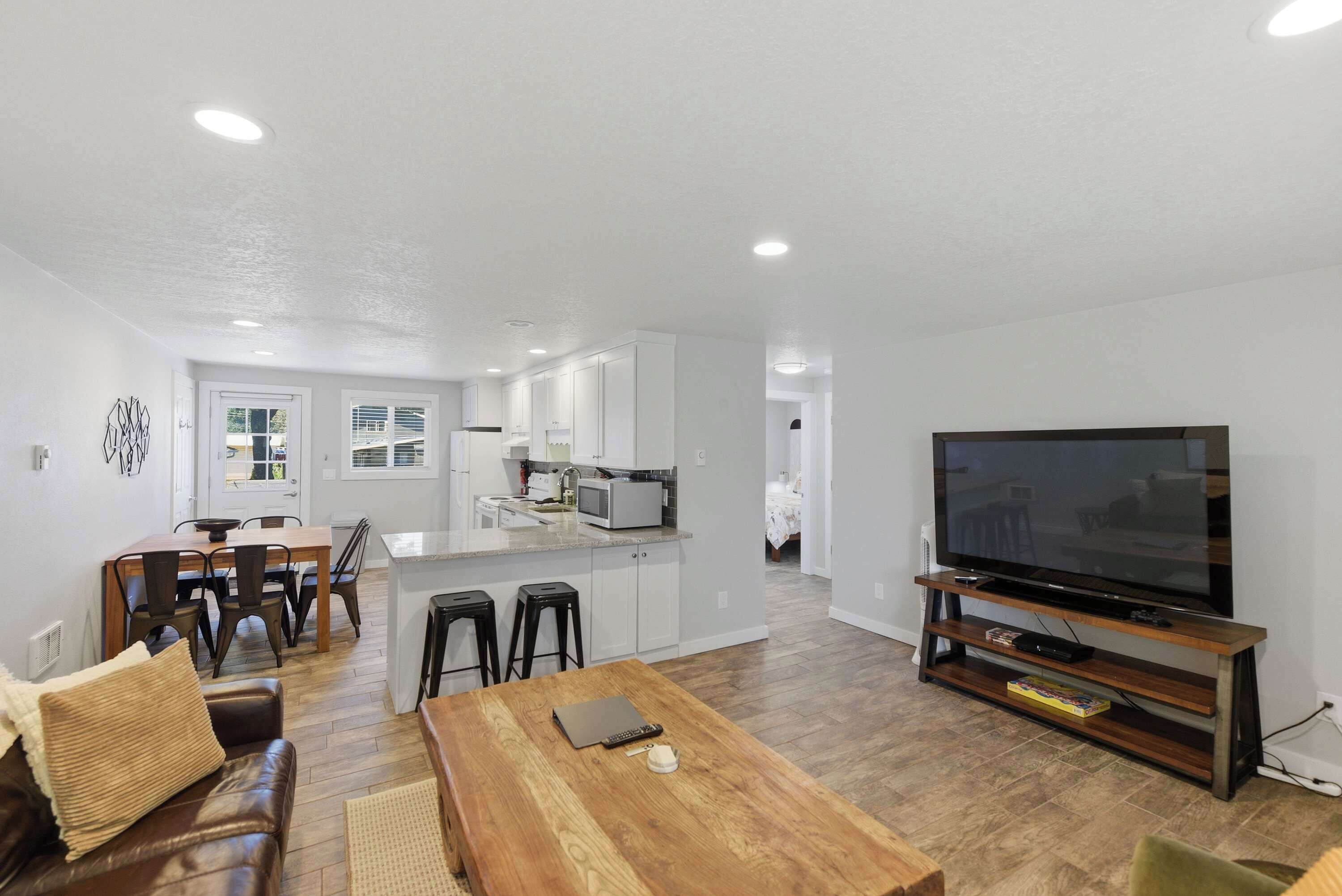 A modern living room with a wooden coffee table, a leather sofa, and a large flat-screen TV on a wooden stand.