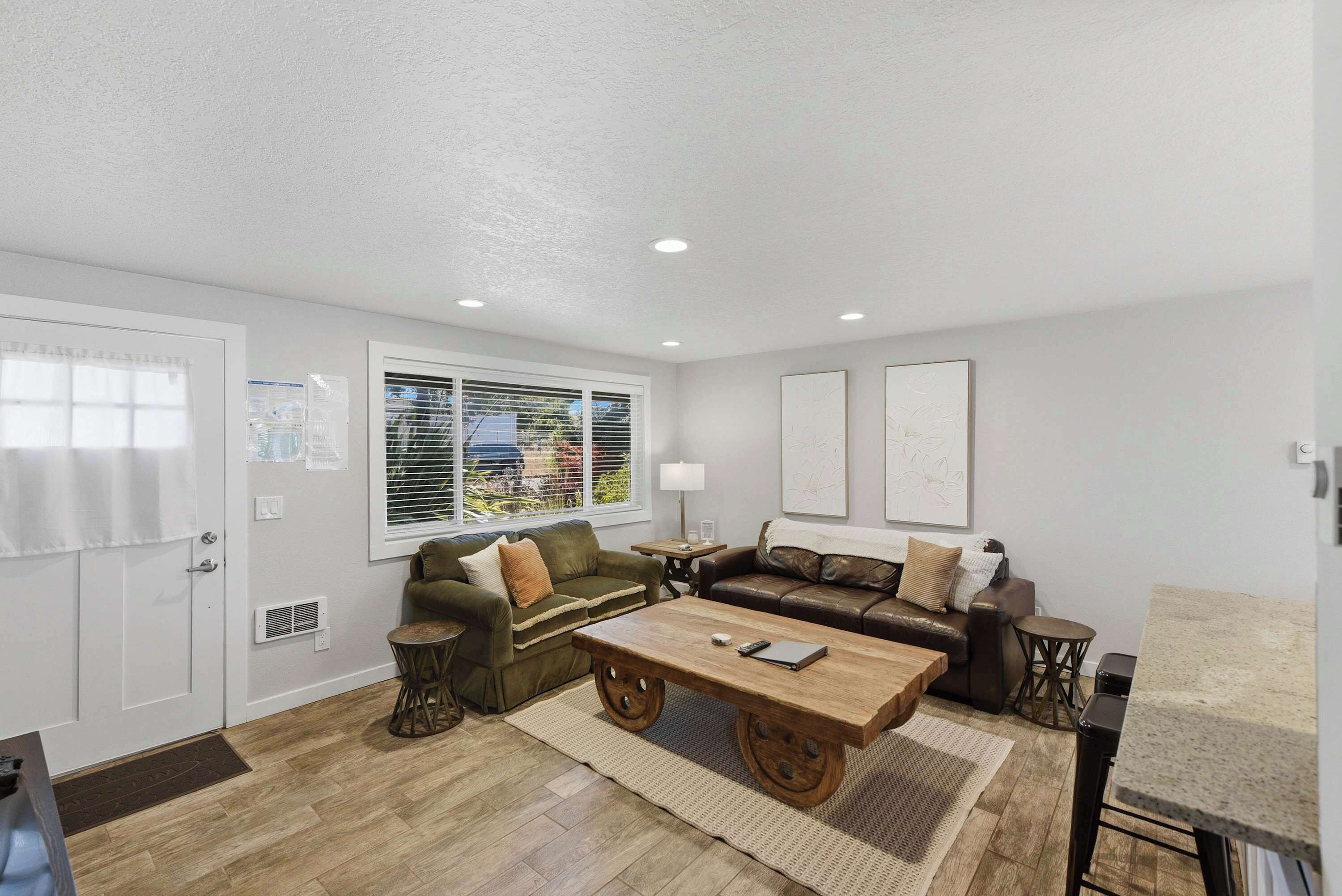 A living room with two sofas, a coffee table, and a window with blinds.