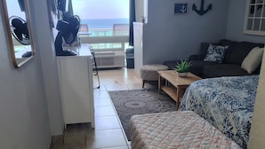 Un espacio habitable compacto con una cama, un escritorio pequeño y vistas al mar.