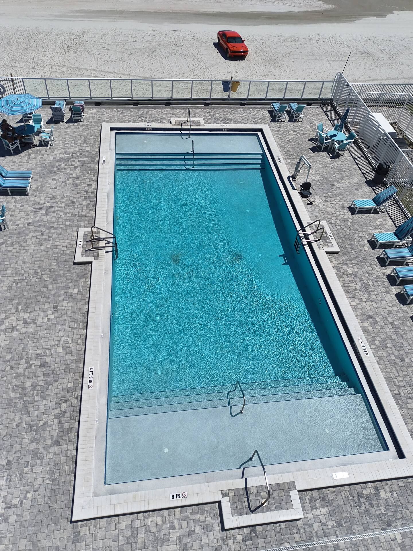 Une piscine rectangulaire entourée d’une terrasse carrelée.