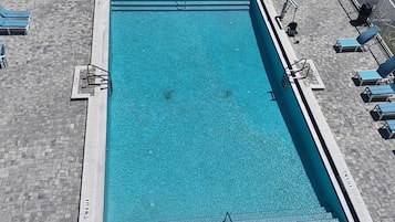 A rectangular swimming pool with a tiled deck surrounding it.