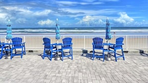 Un patio frente al mar con sillas y sombrillas azules, con vista al océano.