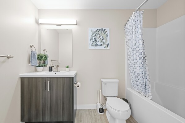Un baño moderno con inodoro, lavamanos y ducha.