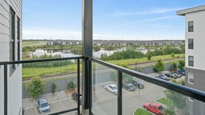 A view from a balcony overlooking a body of water, a parking lot, and a row of houses.