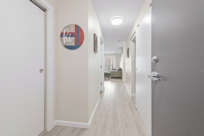 A hallway with a door on the left, a circular sign with text, and a door on the right. - KING BED/ AC/ Henday /Whitemud (Edmonton)