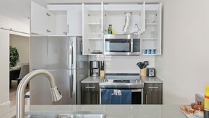 A modern kitchen with stainless steel appliances, white cabinetry, and a built-in microwave.