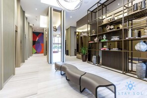 Um lobby de hotel moderno com um longo banco, um balcão de recepção e uma parede colorida e abstrata.