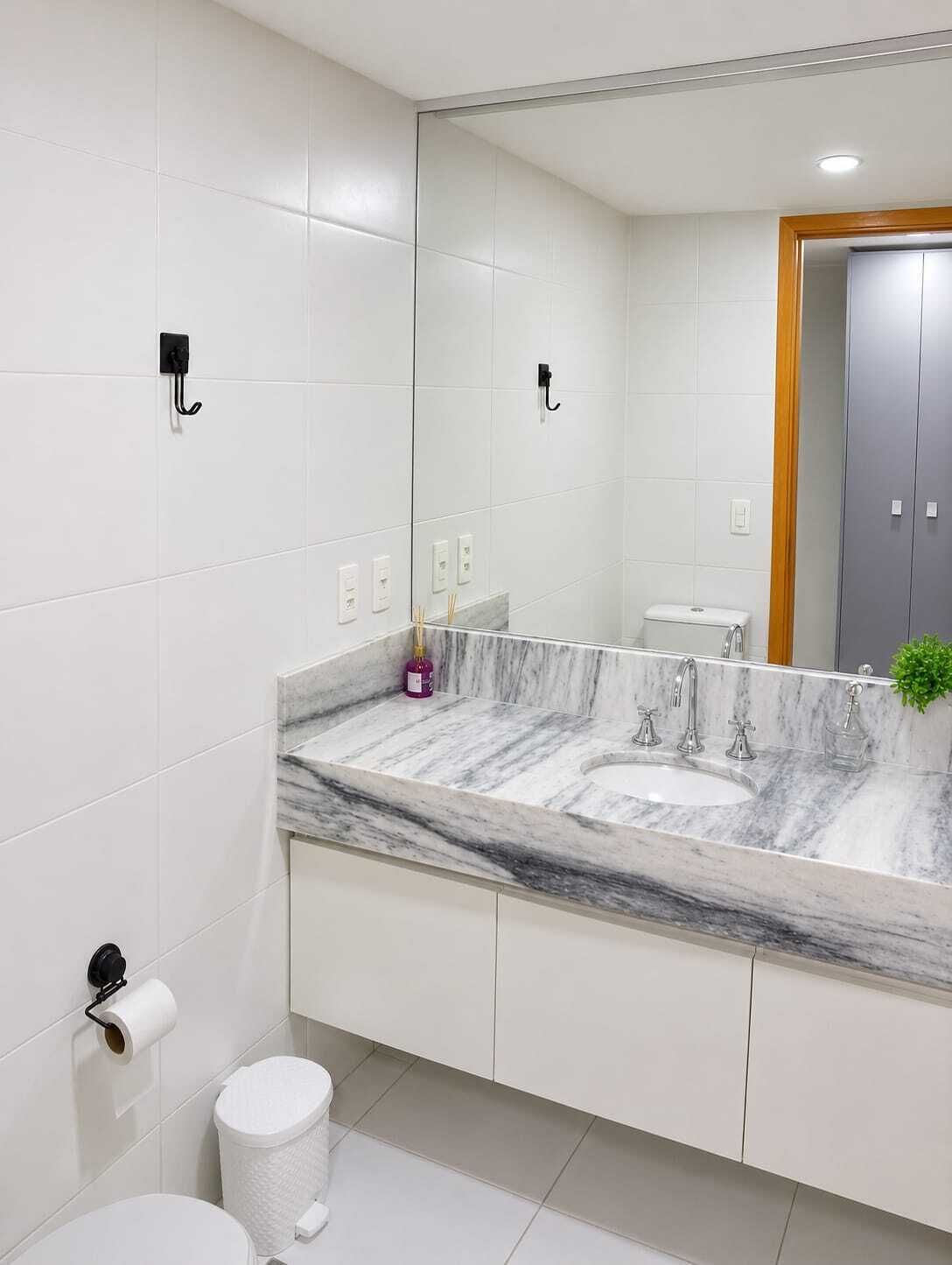 Une salle de bain moderne avec un lavabo en marbre, des carreaux blancs et un grand miroir.
