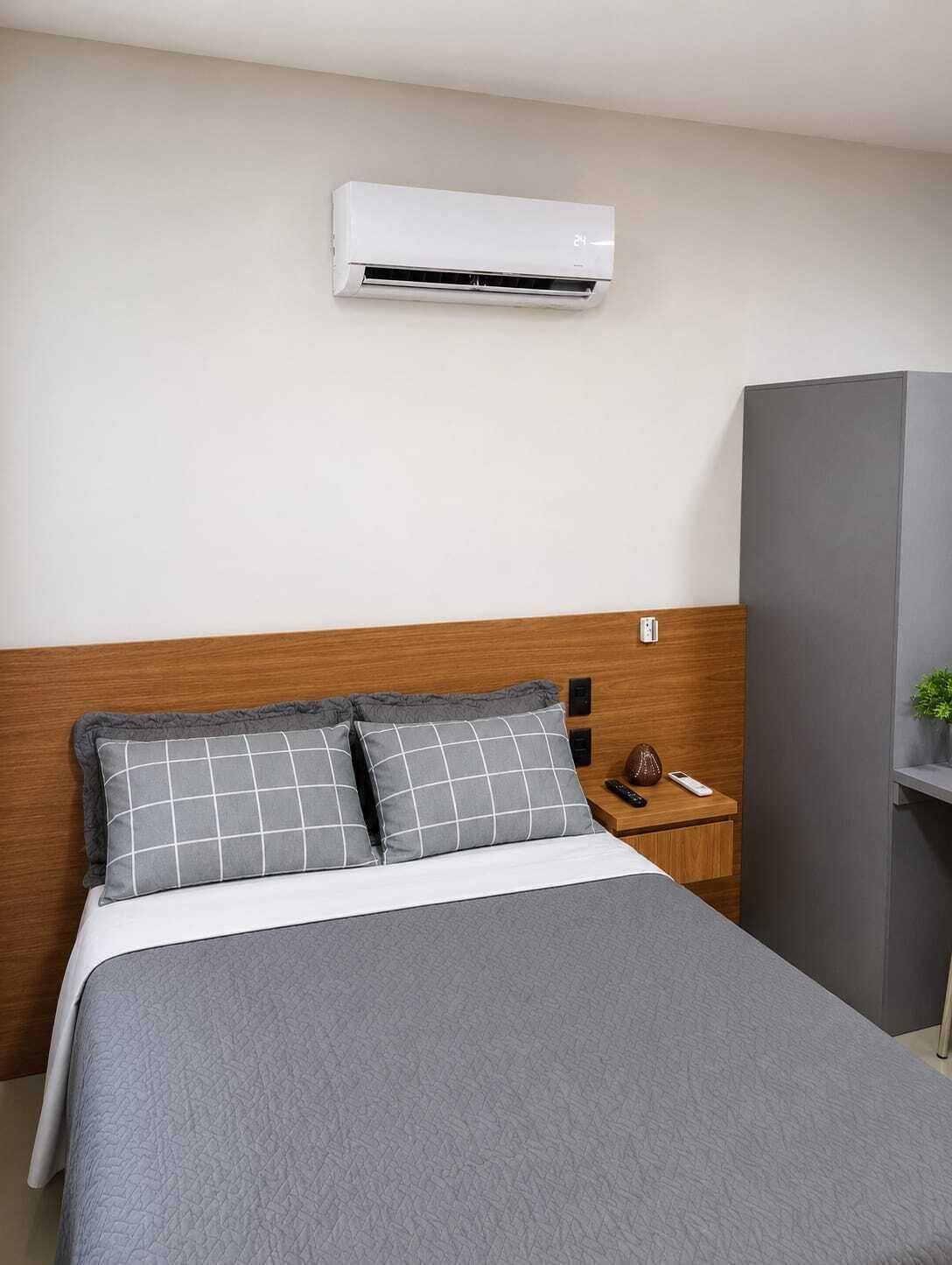 Une chambre d’hôtel comprenant un lit, une table de chevet, une armoire et un appareil de climatisation.