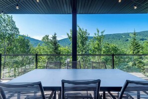 Eine Terrasse mit Tisch und Stühlen mit Blick auf eine gebirgige Landschaft.