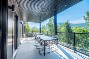 An outdoor terrace with a table and chairs, overlooking a forested landscape.
