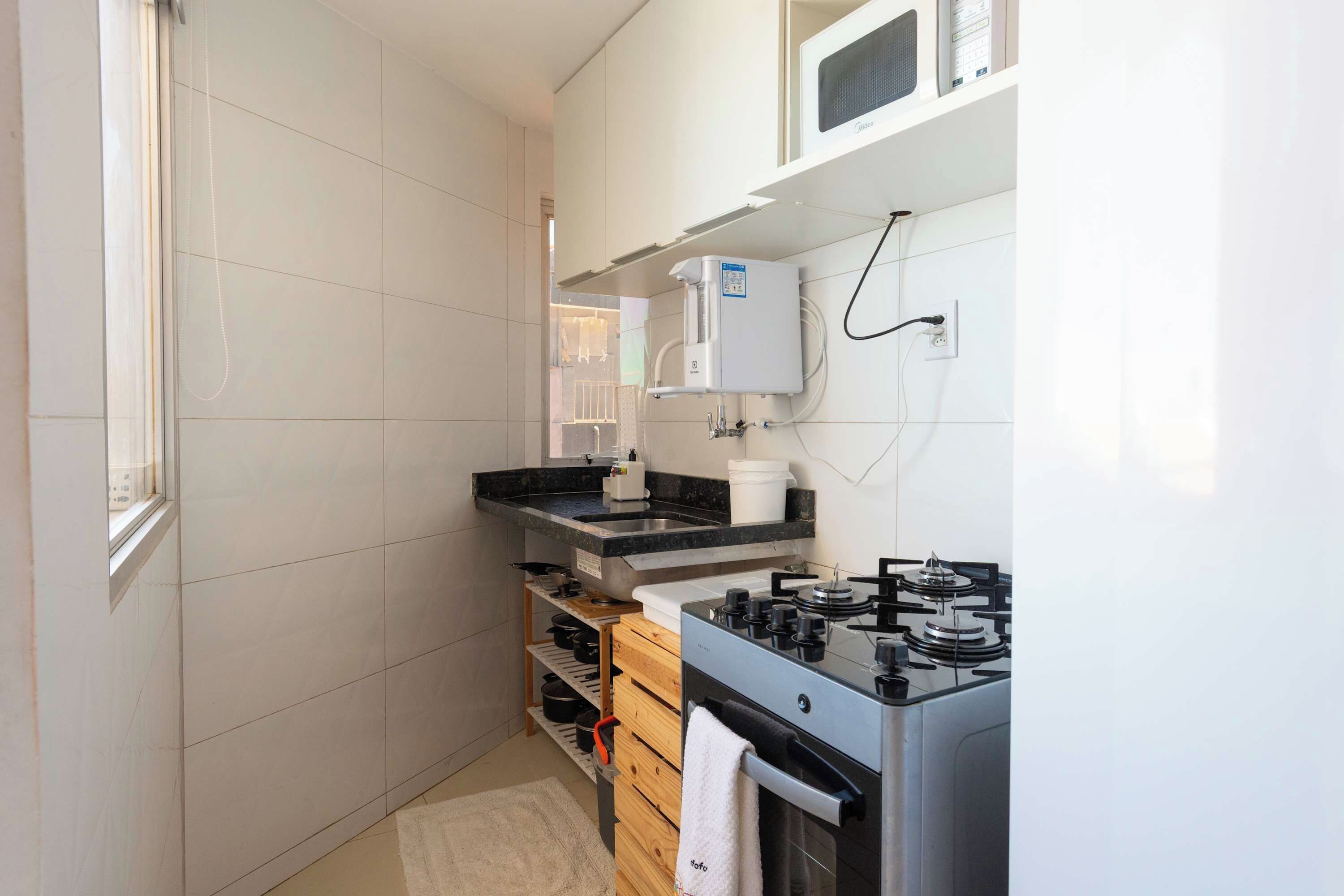 A compact kitchen with a built-in stove, a microwave, and a water heater.