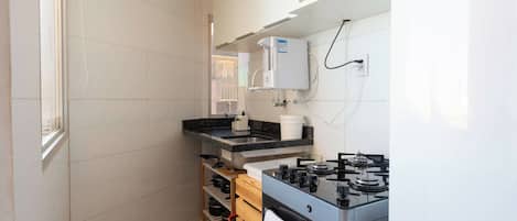 Una cocina compacta con estufa integrada, microondas y calentador de agua.
