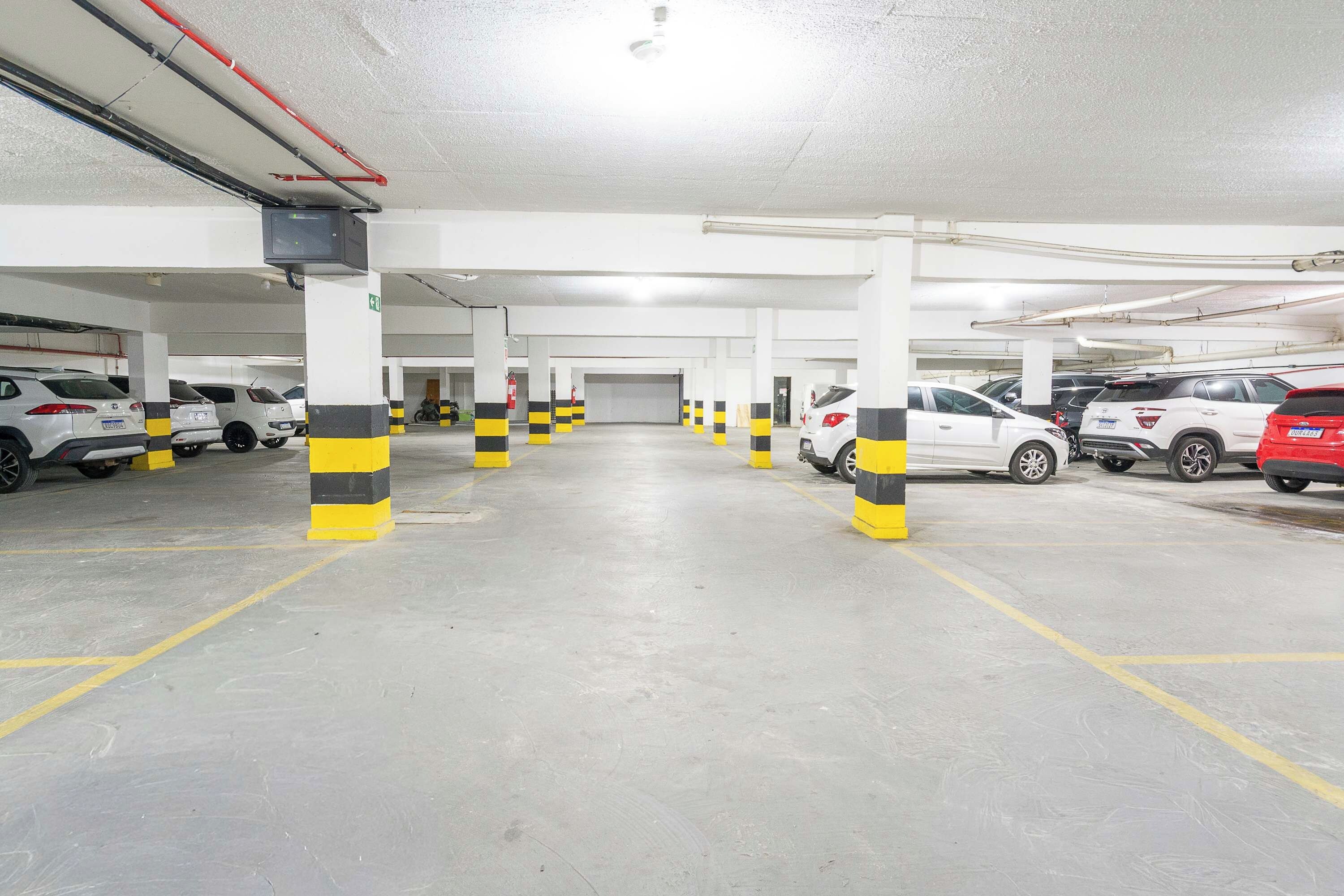 Un estacionamiento subterráneo de varios niveles con espacios delimitados y bolardos rayados de amarillo y negro.