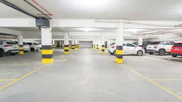 Un estacionamiento subterráneo de varios niveles con espacios delimitados y bolardos rayados de amarillo y negro.