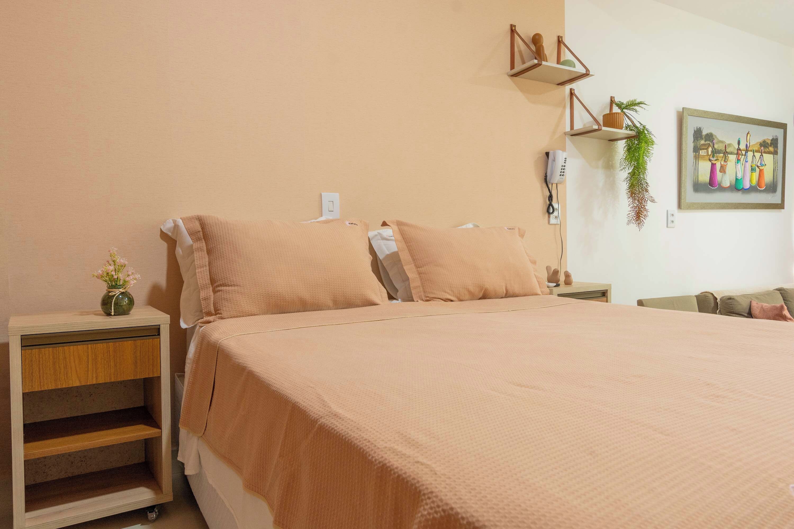 Un dormitorio con una cama grande, mesitas de noche de madera, un estante en la pared y un cuadro.