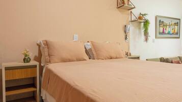 Un dormitorio con una cama grande, mesitas de noche de madera, un estante en la pared y un cuadro.