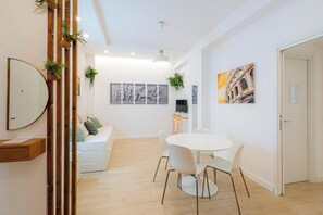 A modern living room with a white sofa, a dining table with chairs, and a TV. - Contessa Elegance Inn Vacation Rental, Rome (Roma)