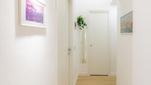 A hallway with a framed picture on the left, a door at the end, and a plant in the center. - Contessa Elegance Inn Vacation Rental, Rome (Roma)