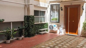 A courtyard with a tiled floor, a wooden door, a window with a metal grill, and potted plants. - Contessa Elegance Inn Vacation Rental, Rome (Roma)