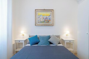 A bedroom with a bed, two bedside tables, and a wall-mounted painting. - Contessa Elegance Inn Vacation Rental, Rome (Roma)