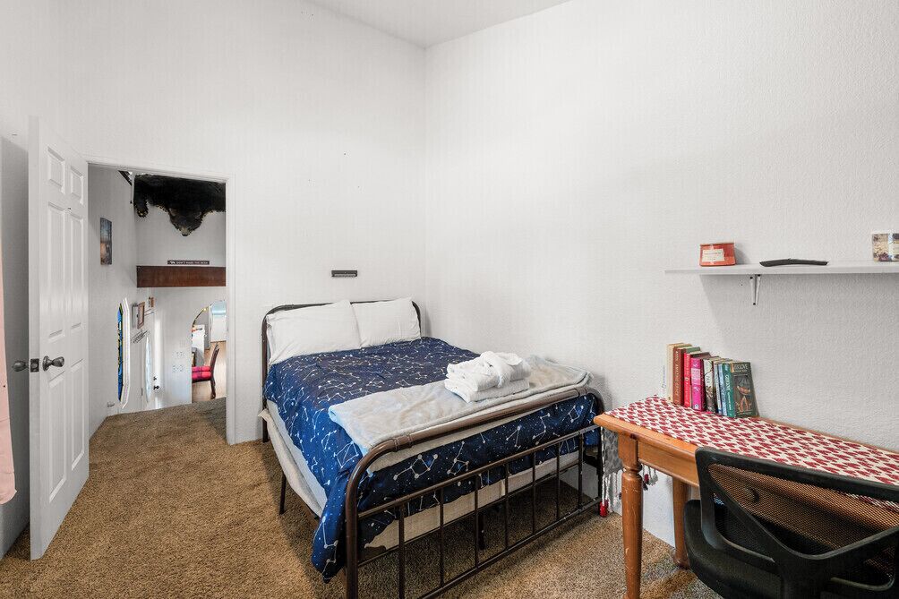 Un dormitorio con una cama, un escritorio y una estantería llena de libros.