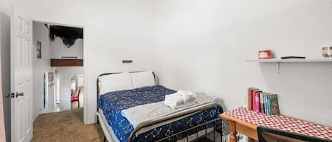Un dormitorio con una cama, un escritorio y una estantería llena de libros.