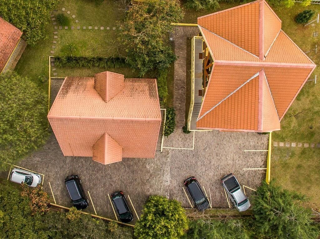 Vista aérea de un edificio con un diseño geométrico singular en su tejado, rodeado de un estacionamiento con varios coches.