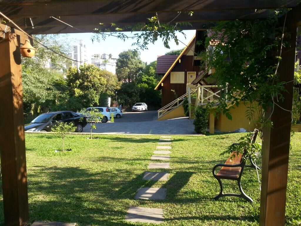 A covered outdoor area with a bench, a pathway, and a building in the background.