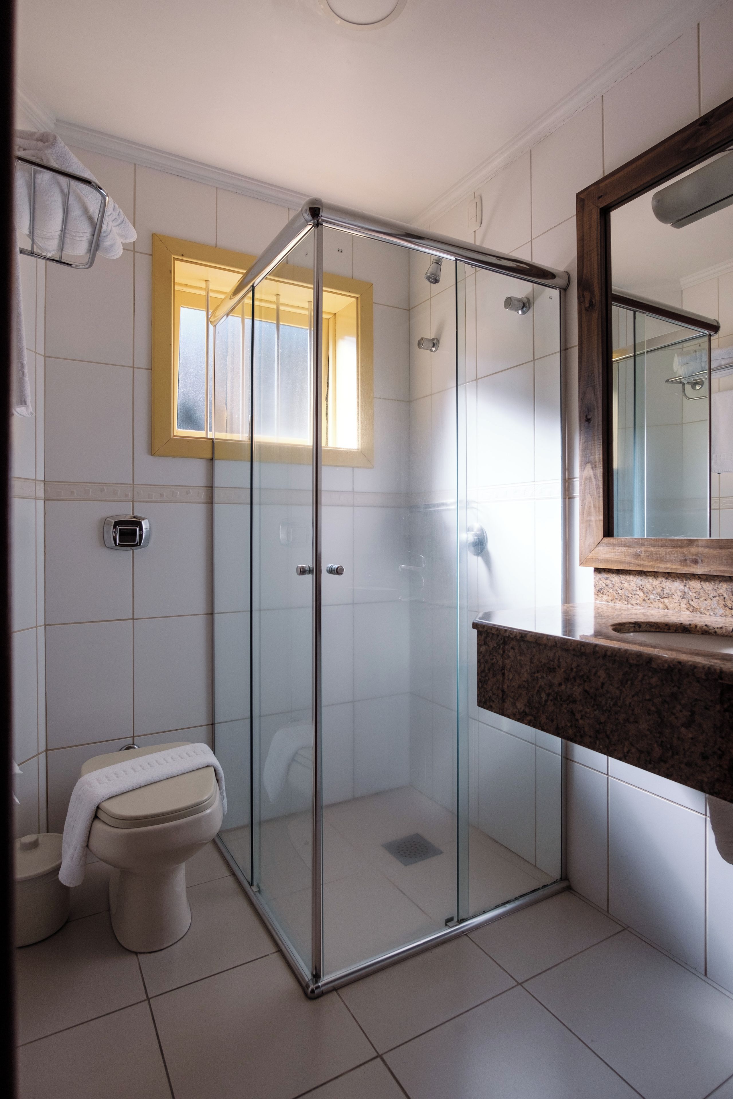 Un baño con ducha de vidrio, inodoro y lavabo con encimera de granito.