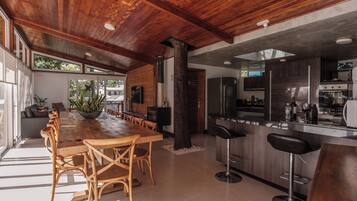 A spacious kitchen with modern appliances, a dining area with wooden furniture, and a large window providing natural light.