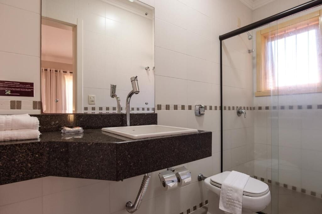 Un baño moderno con ducha envuelta en cristal, un lavabo blanco y un inodoro.