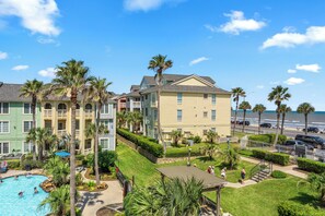 A resort with a swimming pool, palm trees, and a view of the ocean. - Salt & Summer at the Dawn condos with Ocean and Pool Views!  Family friendly! (Galveston)