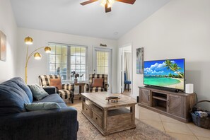 A living room with a sofa, chairs, a coffee table, a television, and a ceiling fan. - Salt & Summer at the Dawn condos with Ocean and Pool Views!  Family friendly! (Galveston)