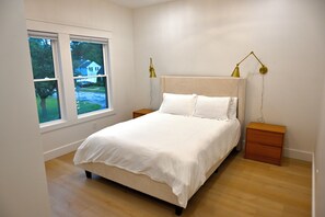 Ein Schlafzimmer mit einem Bett, Nachttischen, einem Fenster mit Aussicht und einer Lampe.