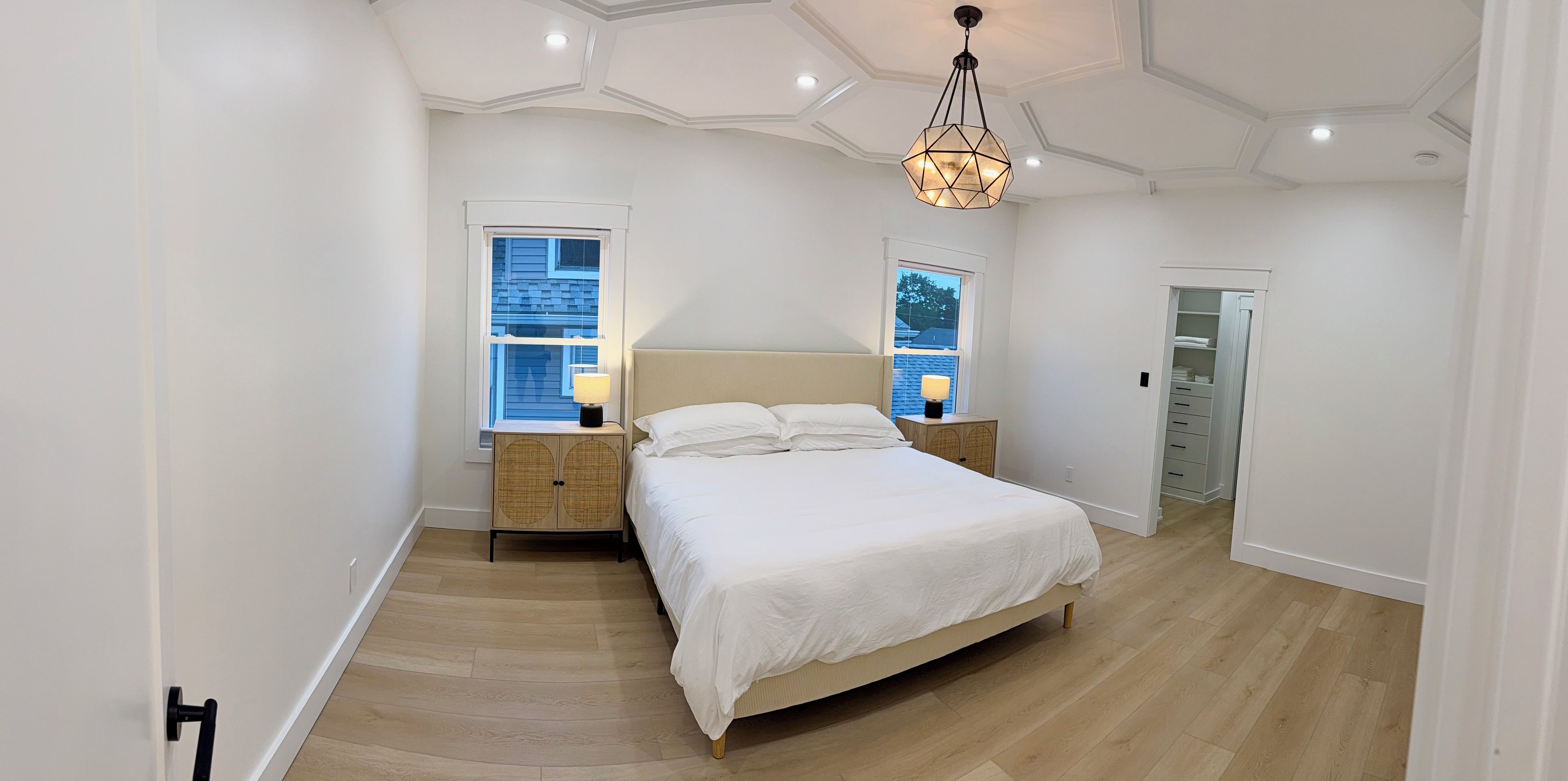 A bedroom with a bed, bedside tables, a wardrobe, and a ceiling light fixture.