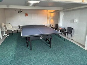 A ping pong table in a room with a green carpet, white walls, and a white door. - Oceanfront Stay on Plum Island Sound (Ipswich)