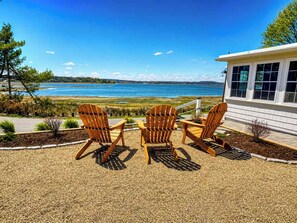 A patio with three wooden Adirondack chairs facing a lake. - Oceanfront Stay on Plum Island Sound (Ipswich)