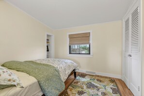A bedroom with a bed, a window with blinds, a door, and a small closet. - Oceanfront Stay on Plum Island Sound (Ipswich)