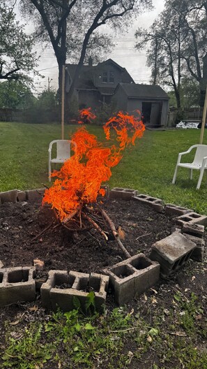 A backyard with a fire pit surrounded by concrete blocks, a wooden deck, and a house in the background. - Relaxing 3-bedroom Retreat W/Big Private backyard (Warren)