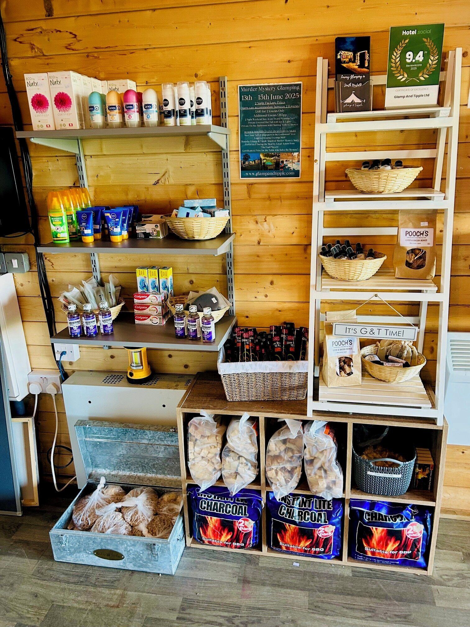 A hotel room with a wooden interior, shelves with toiletries, a calendar, and a basket of snacks.
