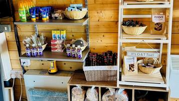 A hotel room with a wooden interior, shelves with toiletries, a calendar, and a basket of snacks.