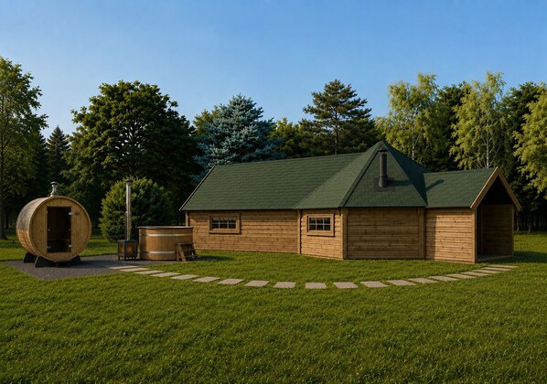 Una cabaña de madera con techo verde, una sauna y un barril grande en un césped.