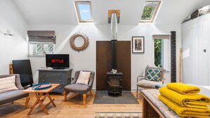 Een moderne woonkamer met een open haard, zithoek en een televisie waarop 'NETFLIX' wordt weergegeven.