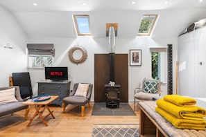 A modern living room with a fireplace, seating area, and a television displaying 'NETFLIX'. - Tea Hut | By My Getaways (Lewes)